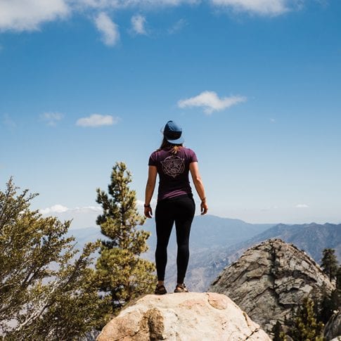 woman standing on mountain ledge