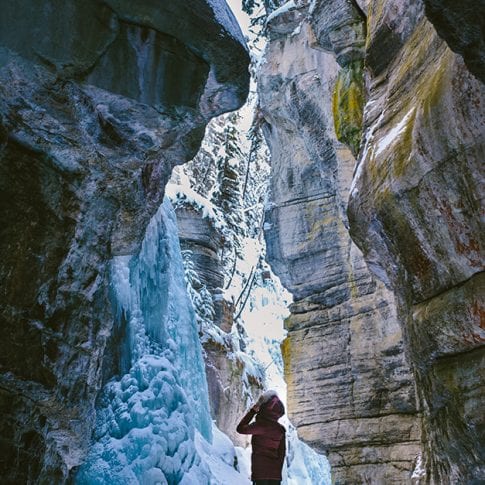 girl standing in canyon with frozen waterfalls